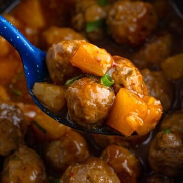 Slow cooker Asian pork meatballs with pineapple and a serving spoon.