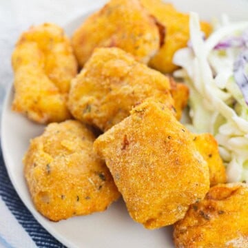 Air Fryer Catfish Nuggets piled on a plate with coleslaw, golden and crispy.