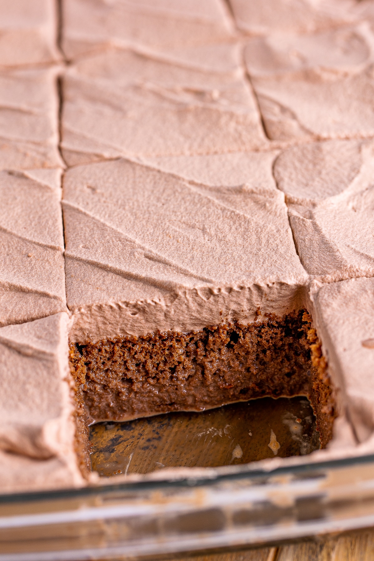 chocolate tres leches cake in the baking dish with a slice taken out