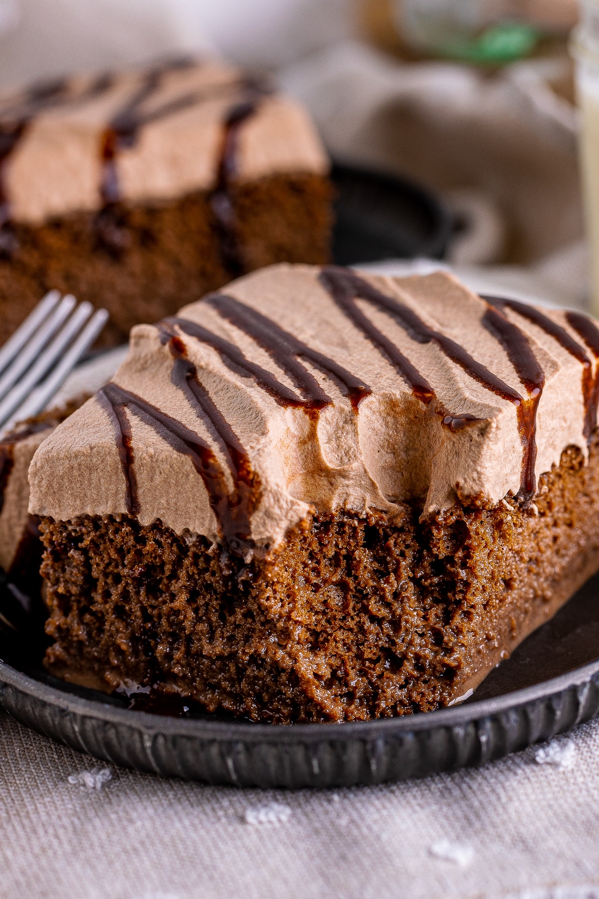 upclose image of a piece of chocolate tres leches cake with a bite taken out