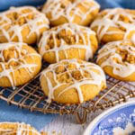 Coffee cake cookies with cinnamon crumble centers and vanilla glaze drizzle on a wire rack.