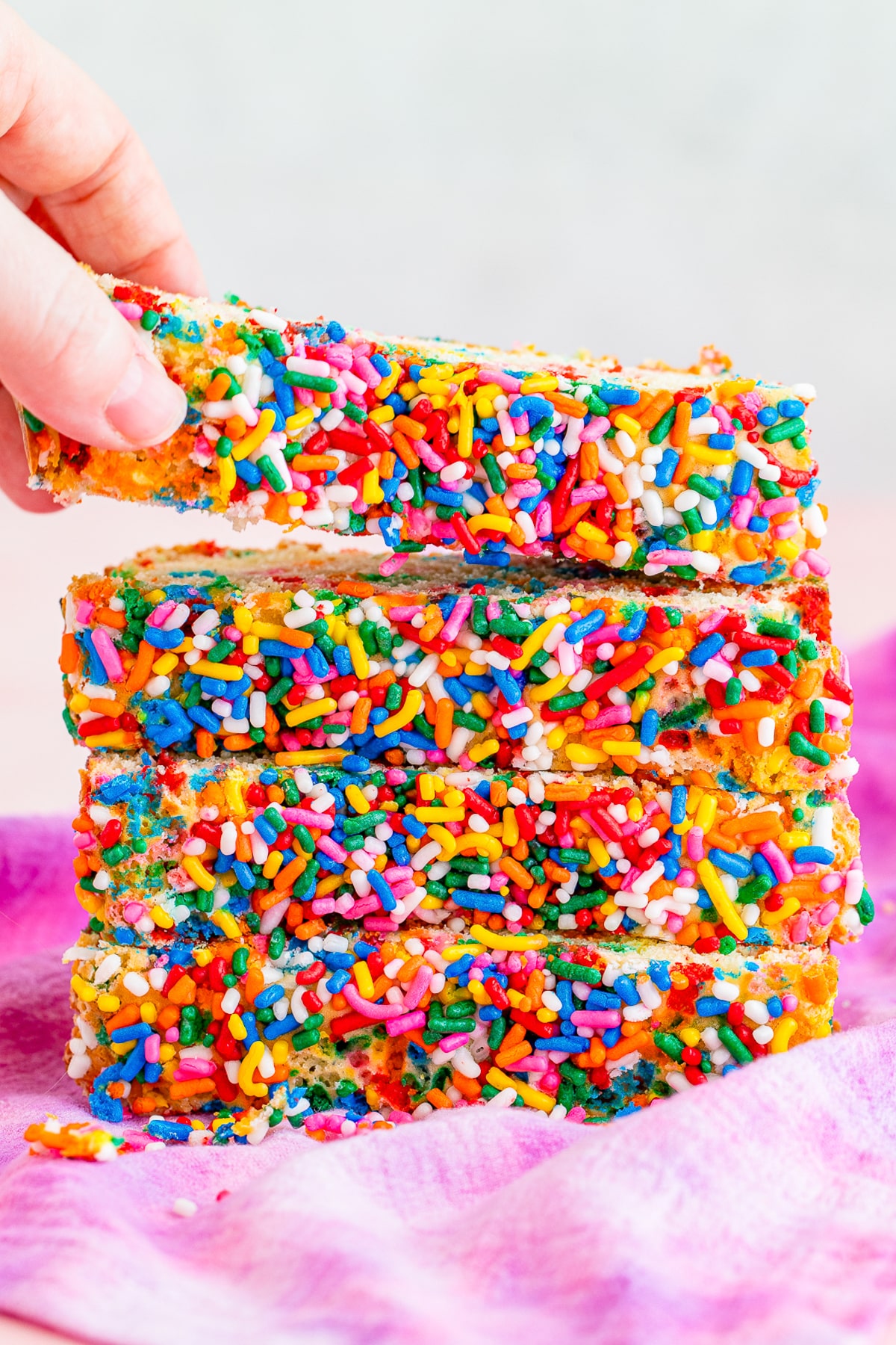 slices of Ice Cream Bread stacked on top of each other, a hand grabbing the top slice