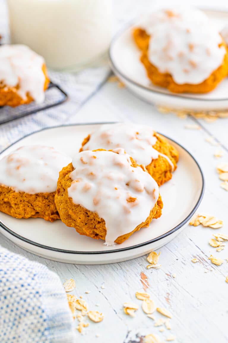 Iced Pumpkin Oatmeal Cookies on a plate with a glass of milk.