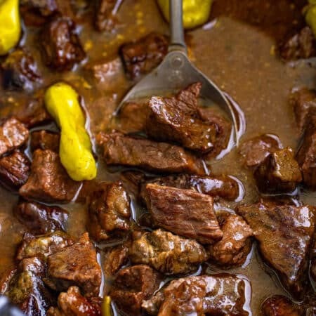 Tender Mississippi steak bites in a buttery au jus and ranch sauce with pepperoncini in a slow cooker.