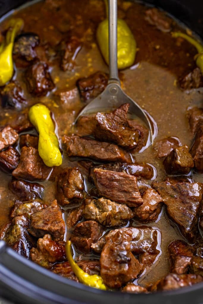 Tender Mississippi steak bites in a buttery au jus and ranch sauce with pepperoncini in a slow cooker.