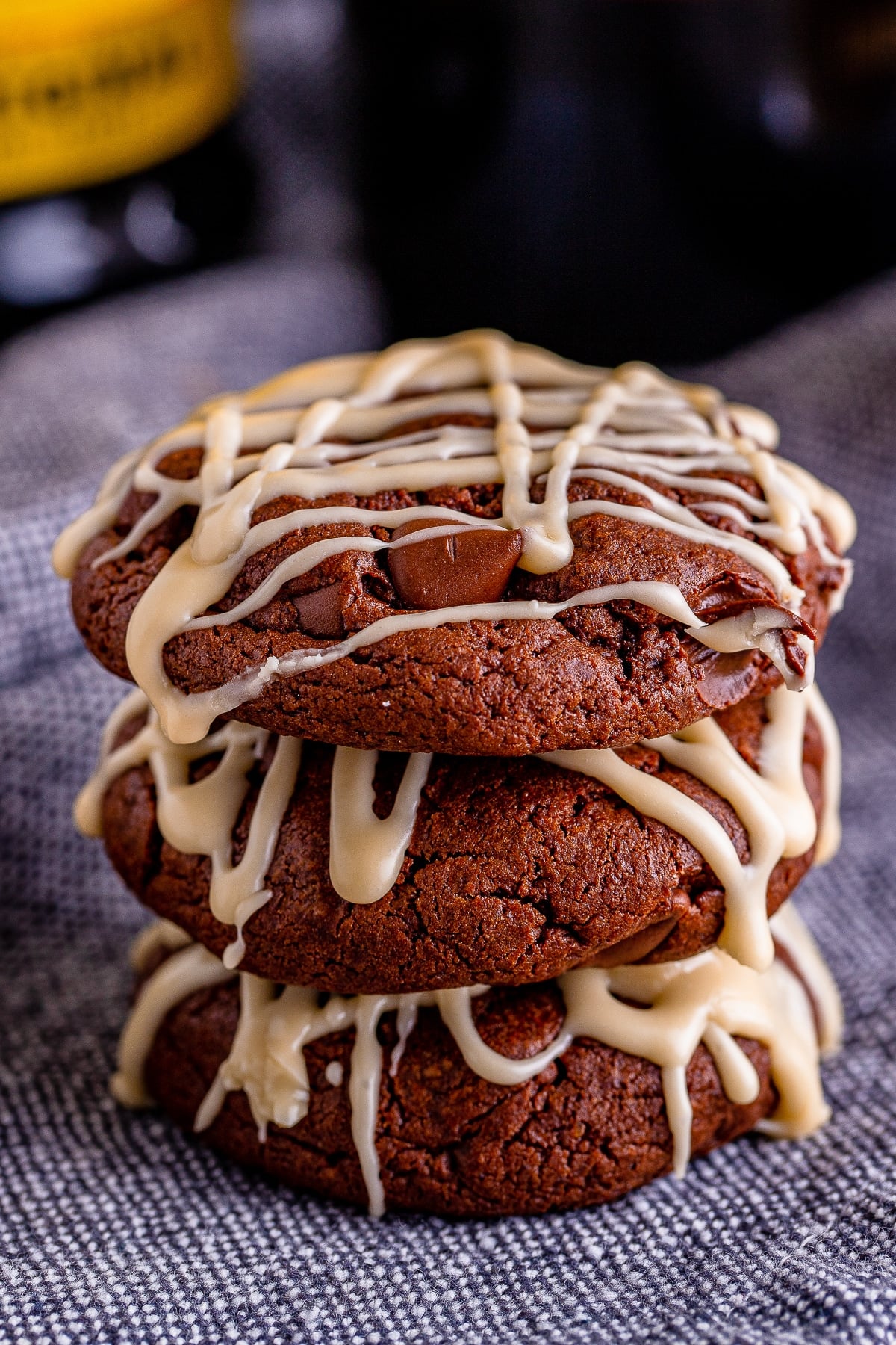 three Chocolate Cookies stacked on top of each other sitting on a grey linen