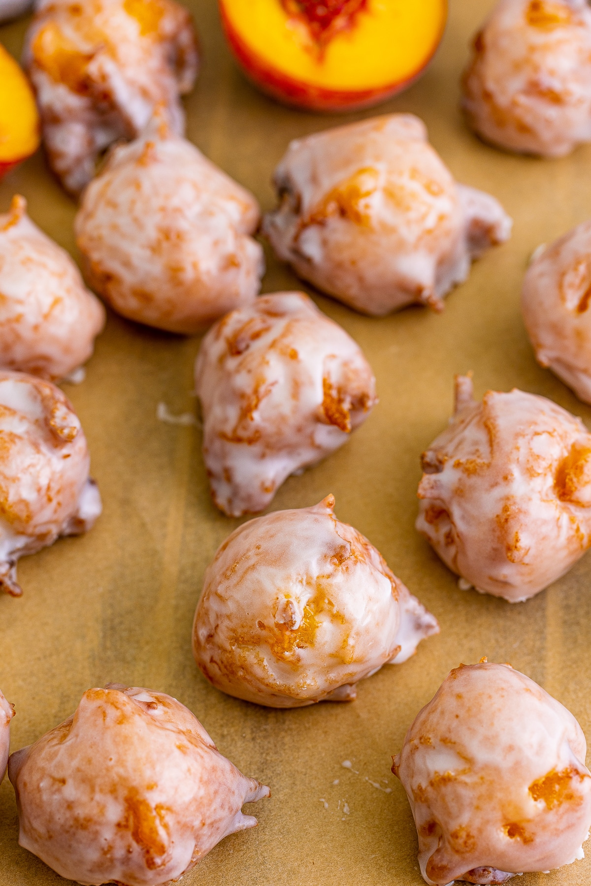 up close image of Peach Fritters that have been glazed on brown parchment paper