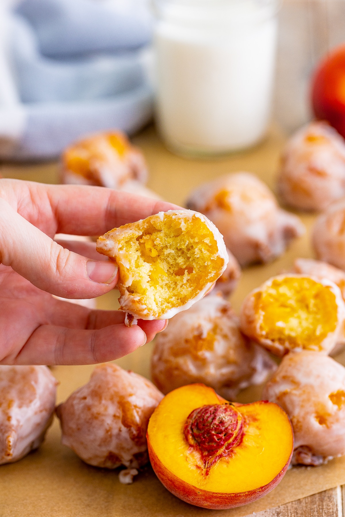 a hand holding up one Peach Fritters that has a bite taken out to see the interior