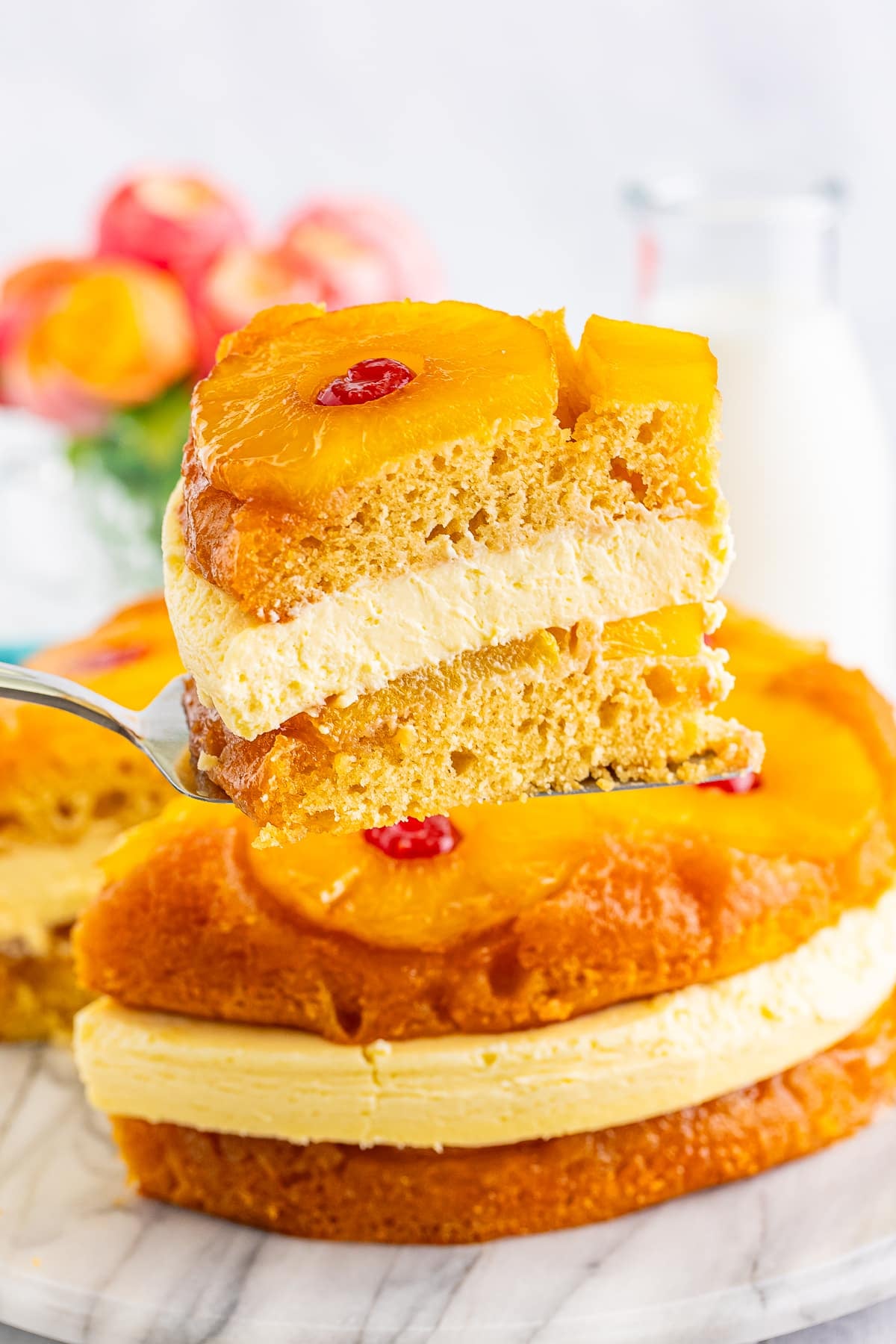 a cake server holding up a slice of pineapple upside down cheesecake in air