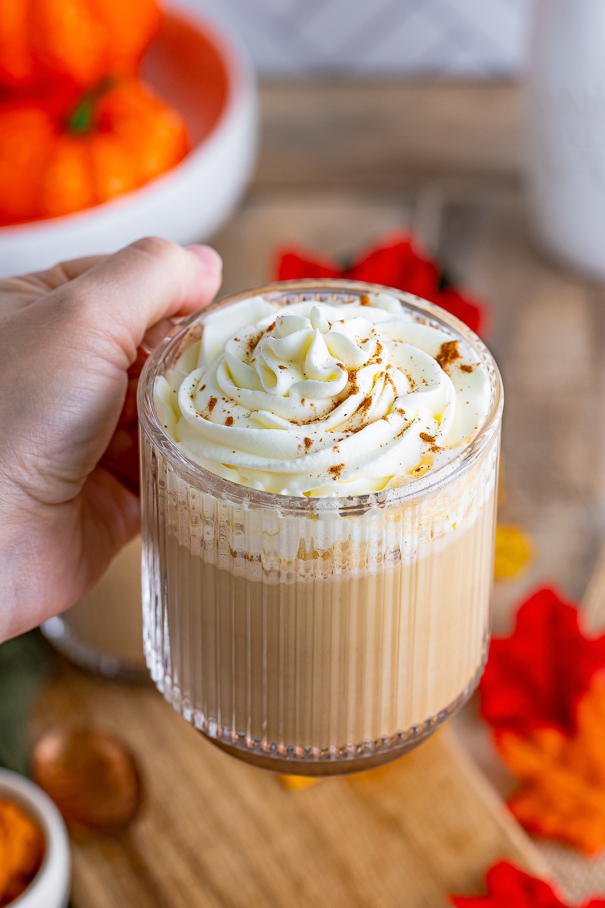 a hand holding up a Pumpkin Spice Latte in air