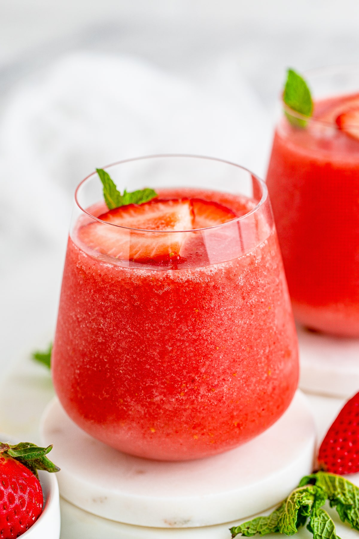 Wine Slushies garnished with sliced strawberries and mint in wine glasses
