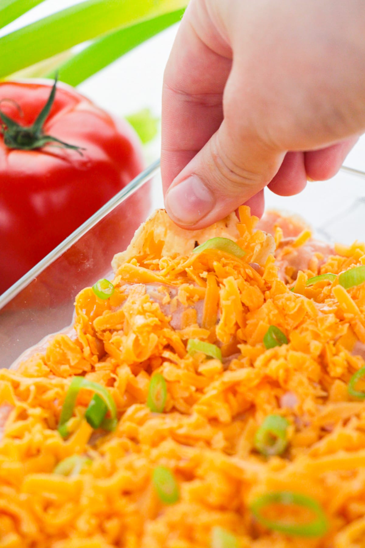 a hand dipping a chip into Taco Dip Recipe