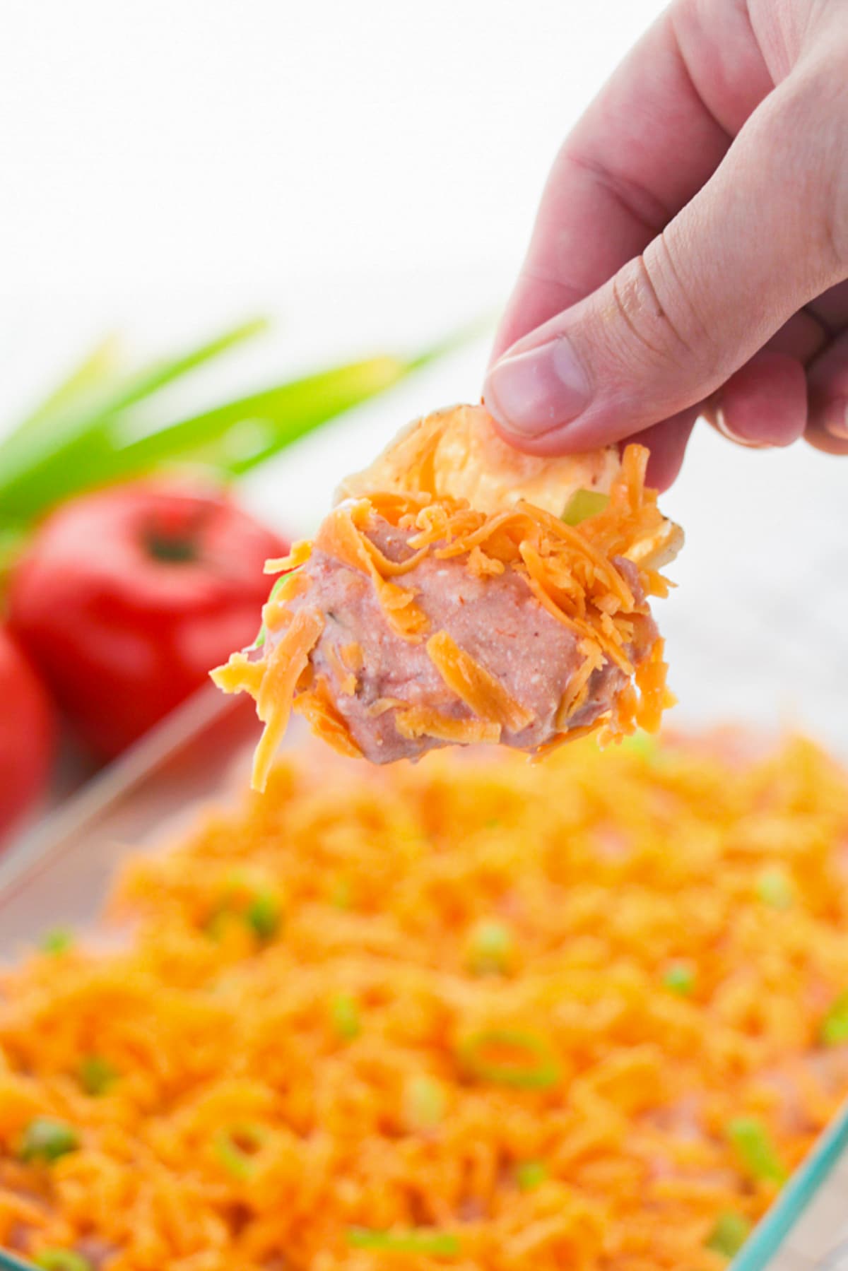 a hand holding up a chip that has been dipped into Taco Dip Recipe in air