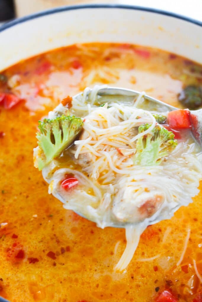 a ladle scoping out a serving of Thai Red Curry Soup in air