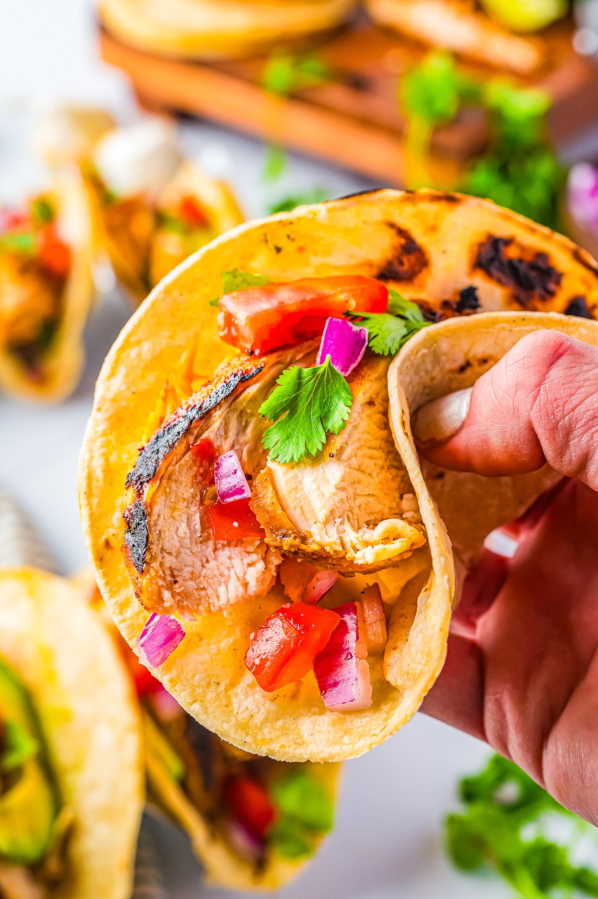 a hand holding up Chicken Tacos in air