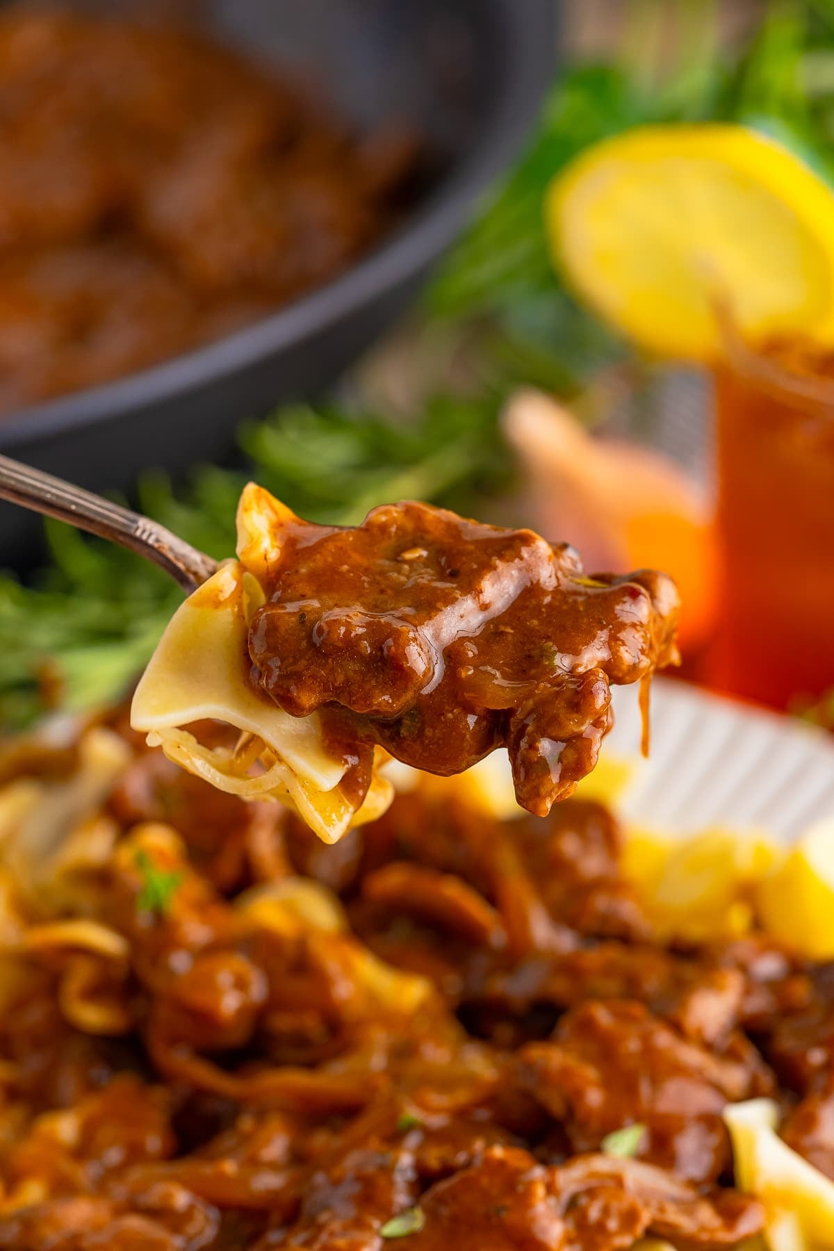 Steakhouse Beef Tips with Noodles, Flank Steak Thinly Sliced and Smothered In A Delicious Steak Sauce Gravy, Caramelized Onions, and Noodles! Recipe from ThisSillyGirlsKitchen.com a spoon holding up a bite of Beef Tips with Noodles