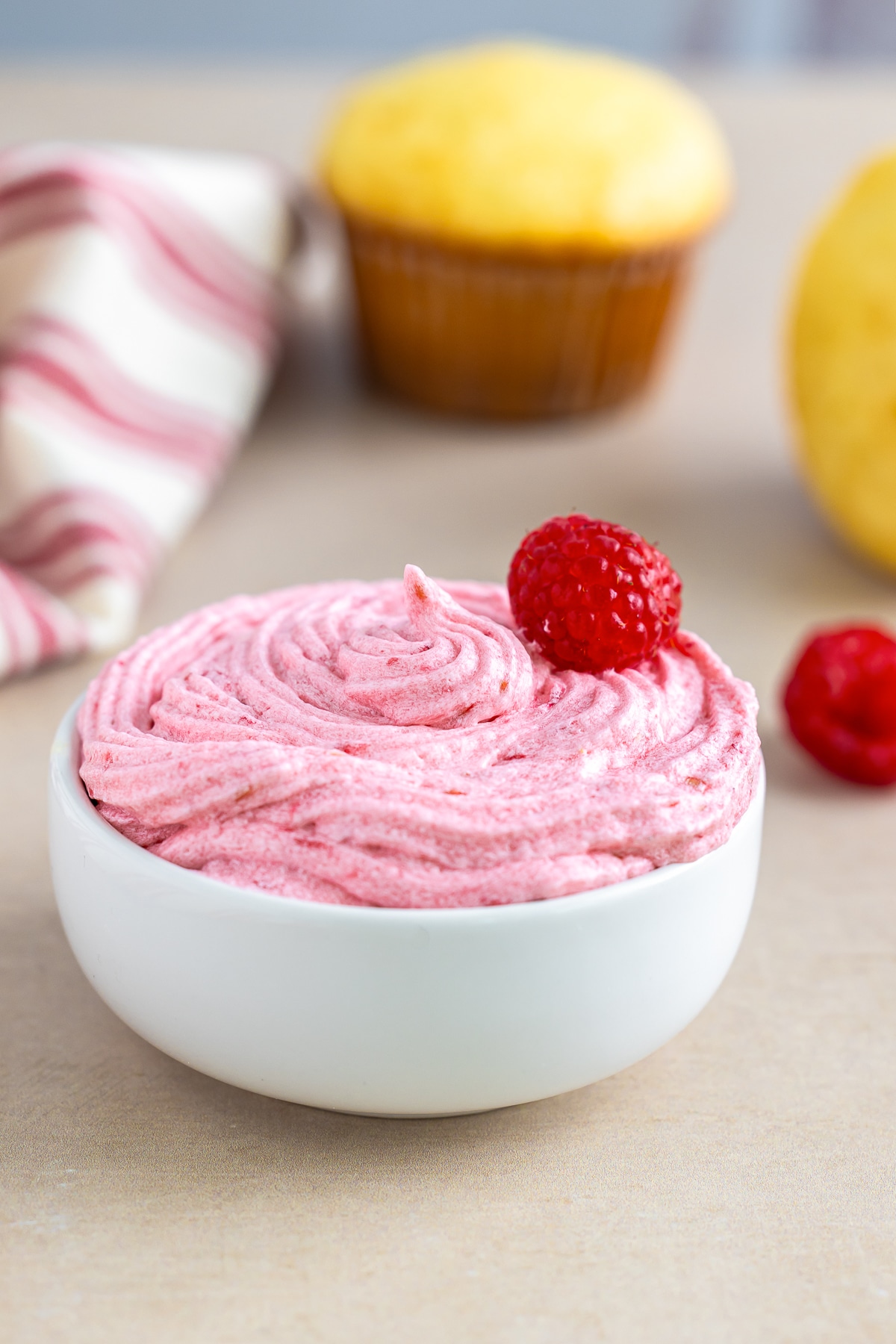 Raspberry Frosting piped into a small white bowl with fresh raspberry