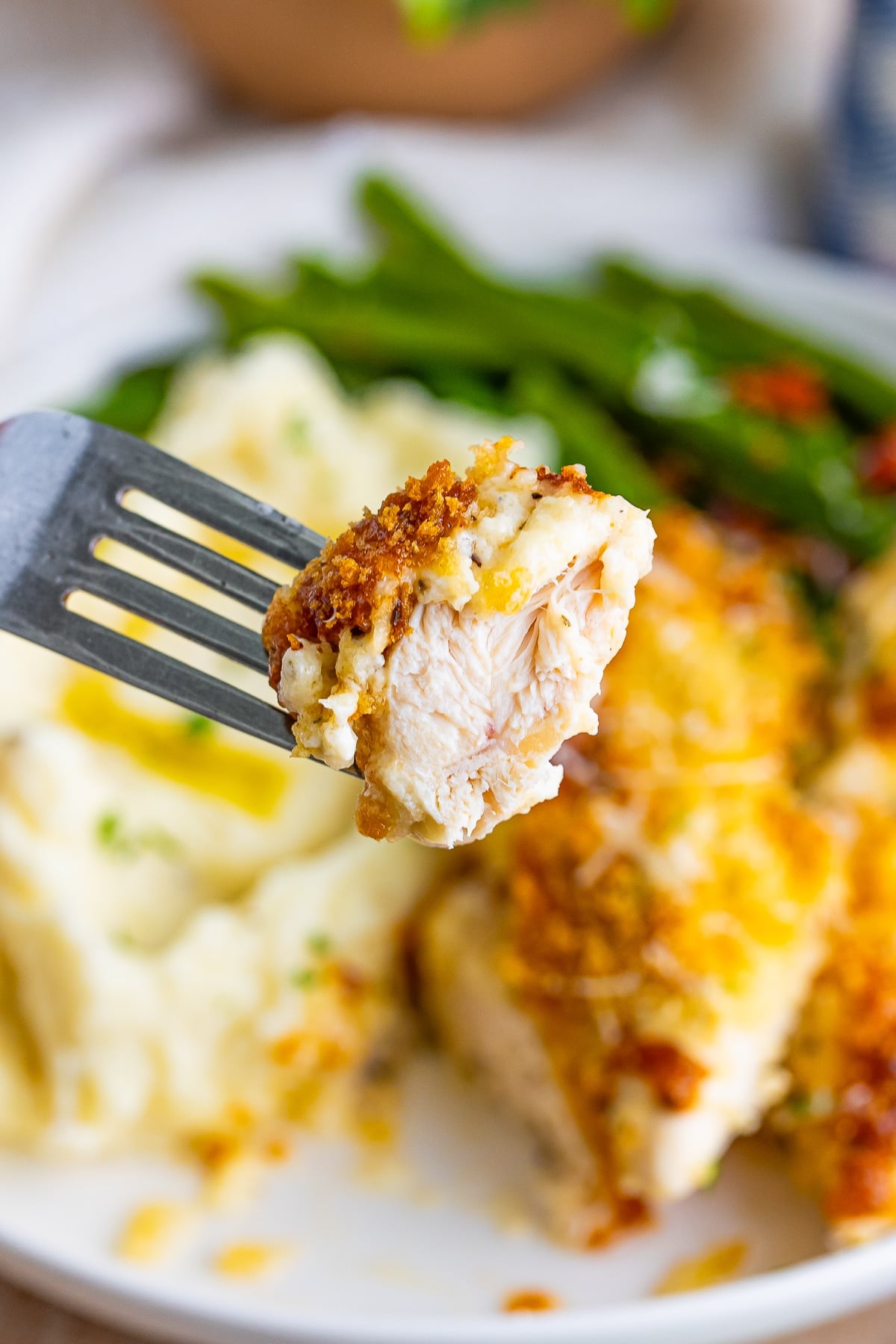 a fork holding up a bite of Oven Baked Chicken Tenders in air