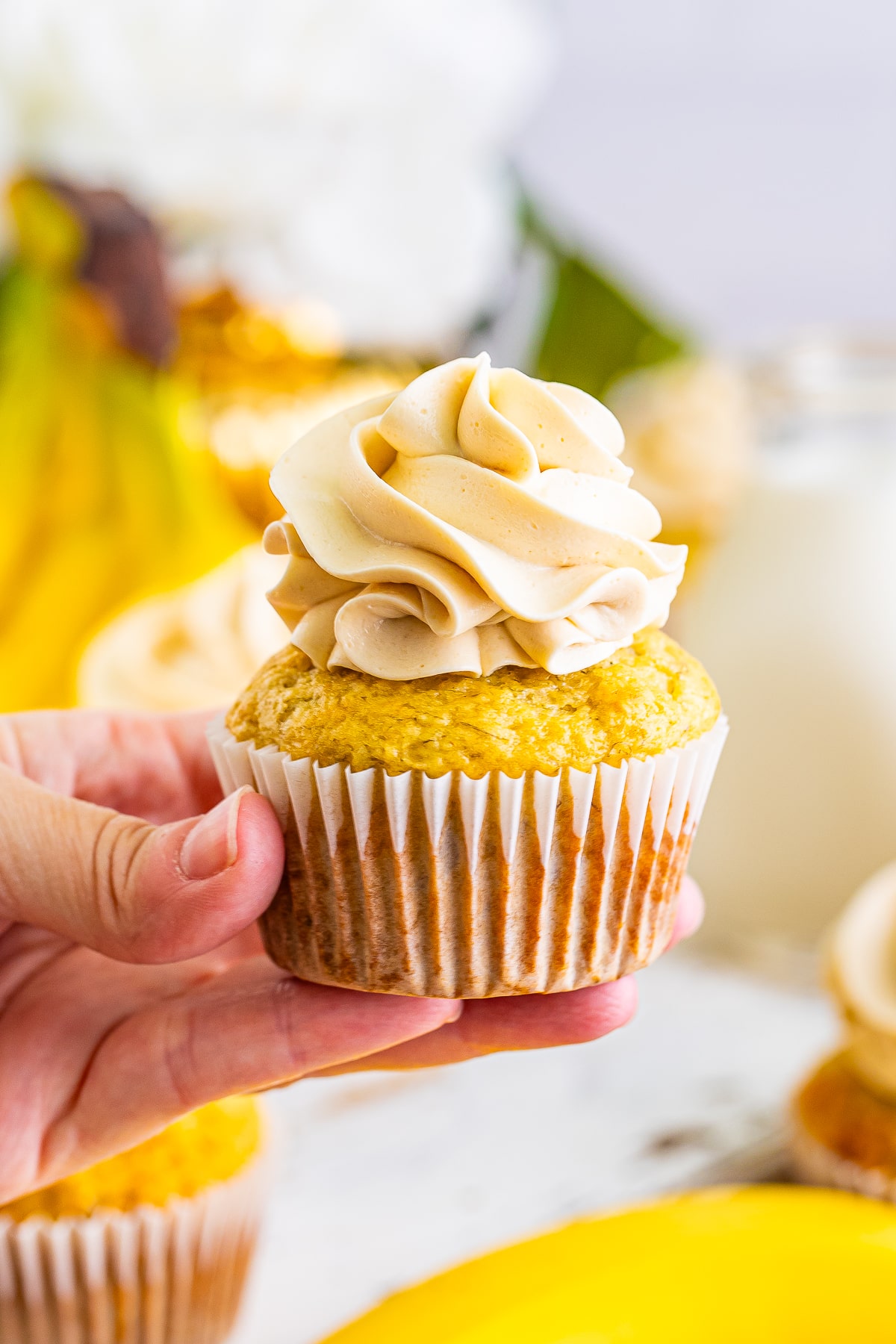 a hand holding up Banana Cupcakes in air