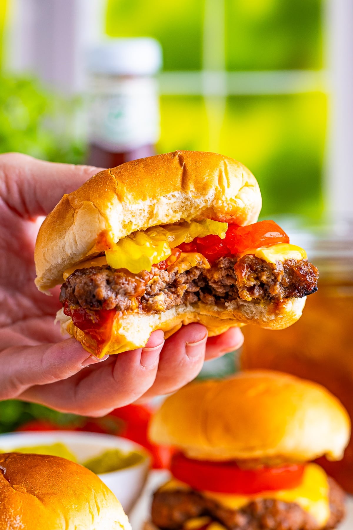 a hand holding up Mini Burger Sliders that has had a bite taken out in air