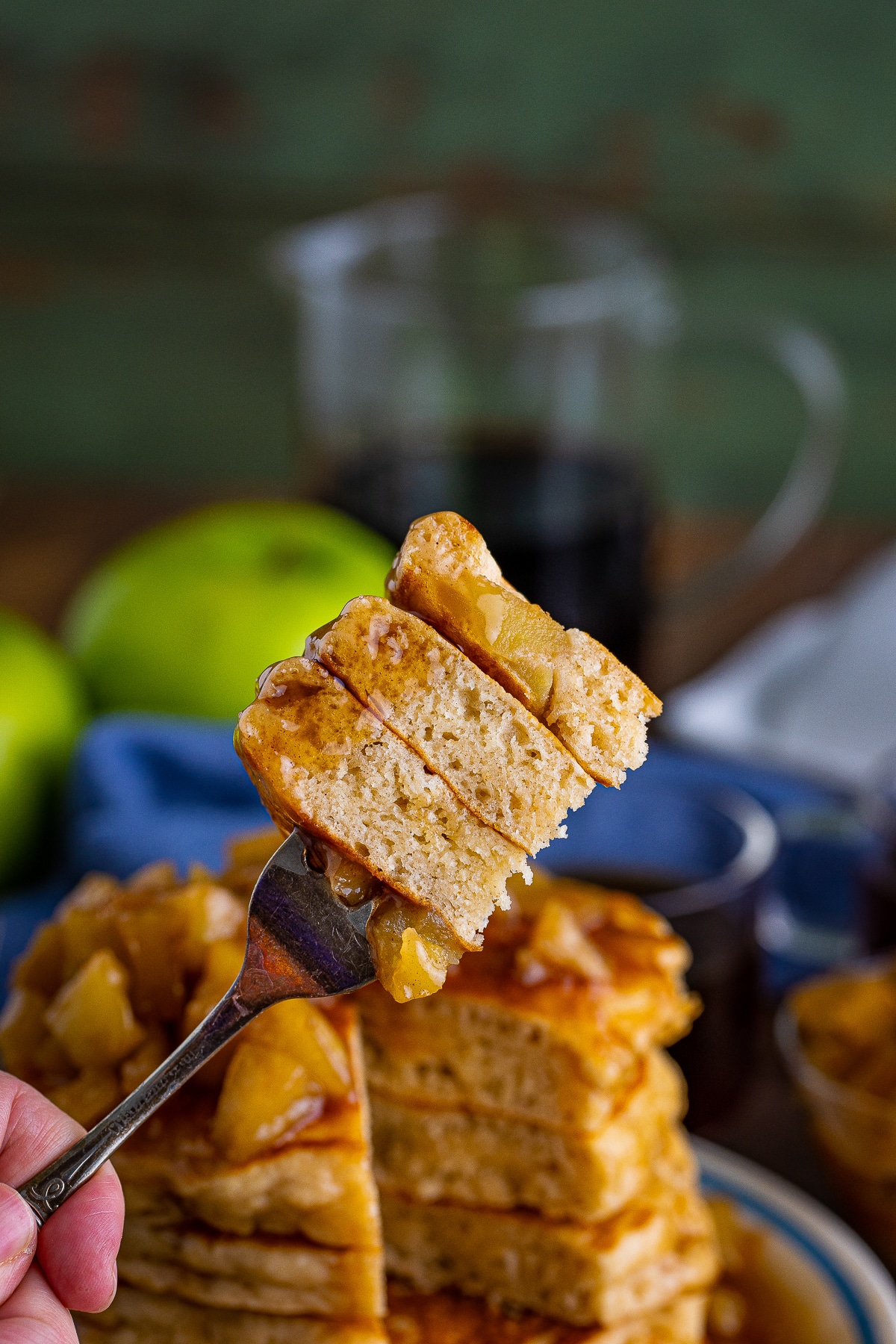 a fork holding up a bite of Apple Pancakes Recipe in air