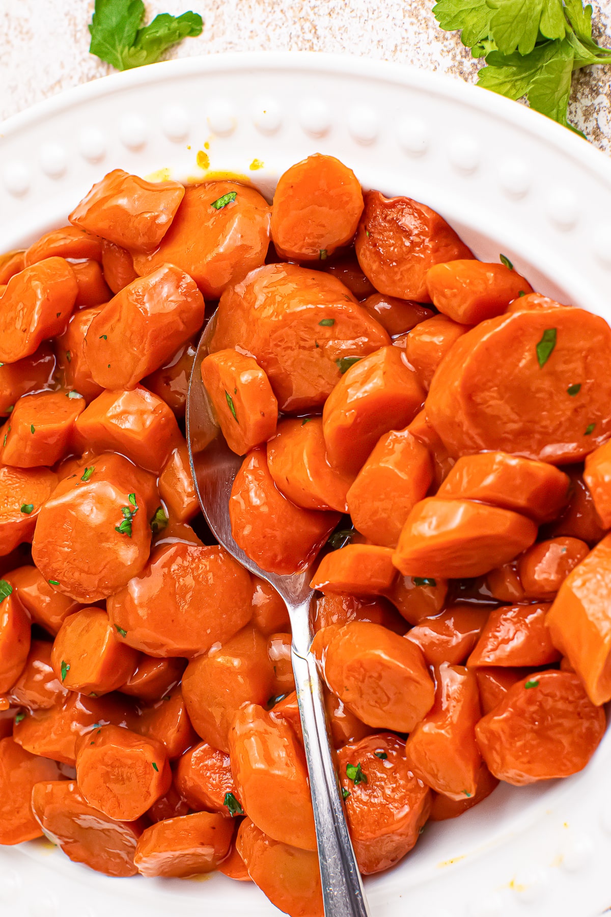 up close image of Maple Glazed Carrots with a spoon on a white plate