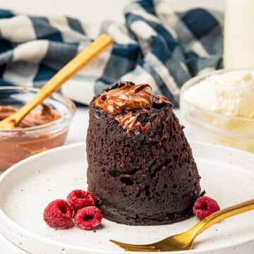 Nutella Mug Cake turned out onto a plate with fresh raspberries.