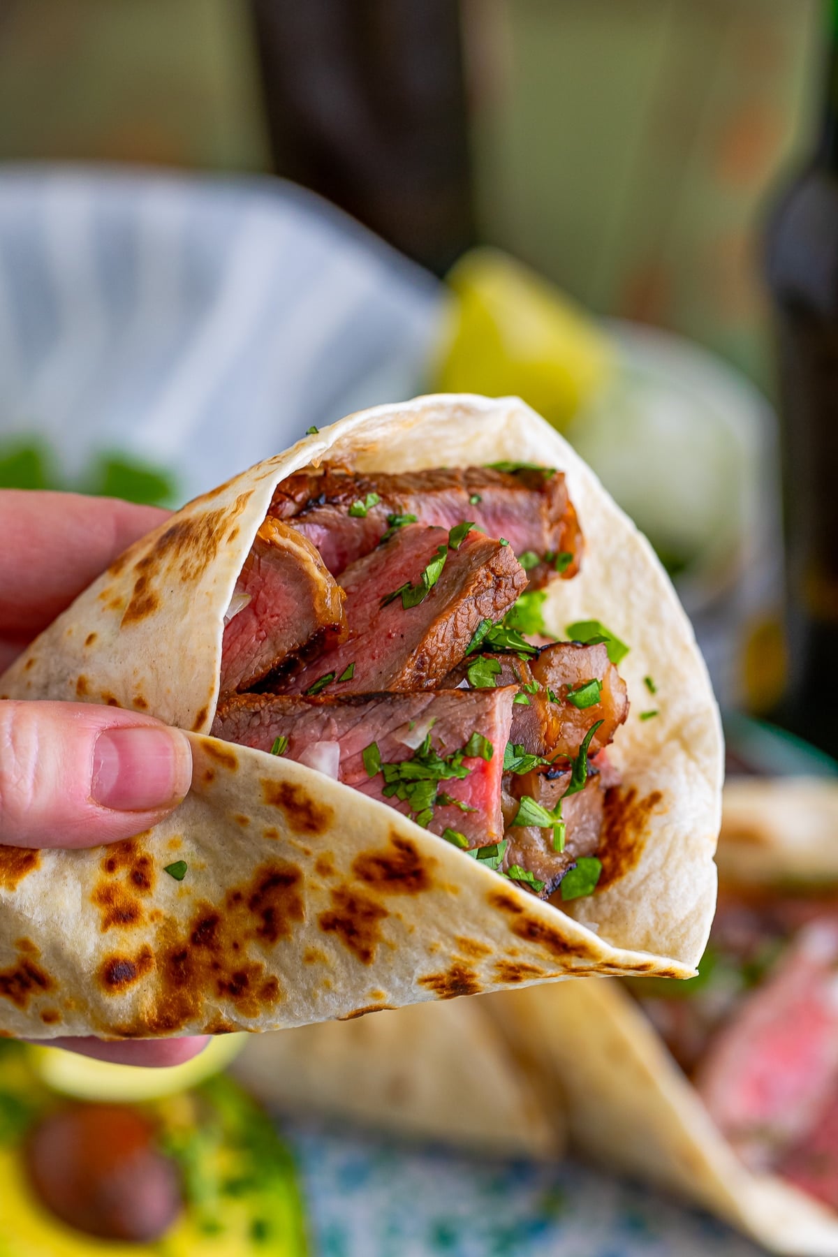 a hand holding up Carne Asada Tacos Recipe in air