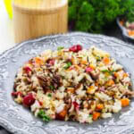 Wild Rice Pilaf with pecans and cranberries served on a gray scalloped plate with fresh parsley.