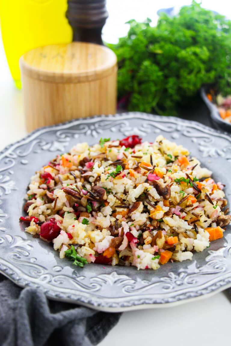 Wild Rice Pilaf with pecans and cranberries served on a gray scalloped plate with fresh parsley.