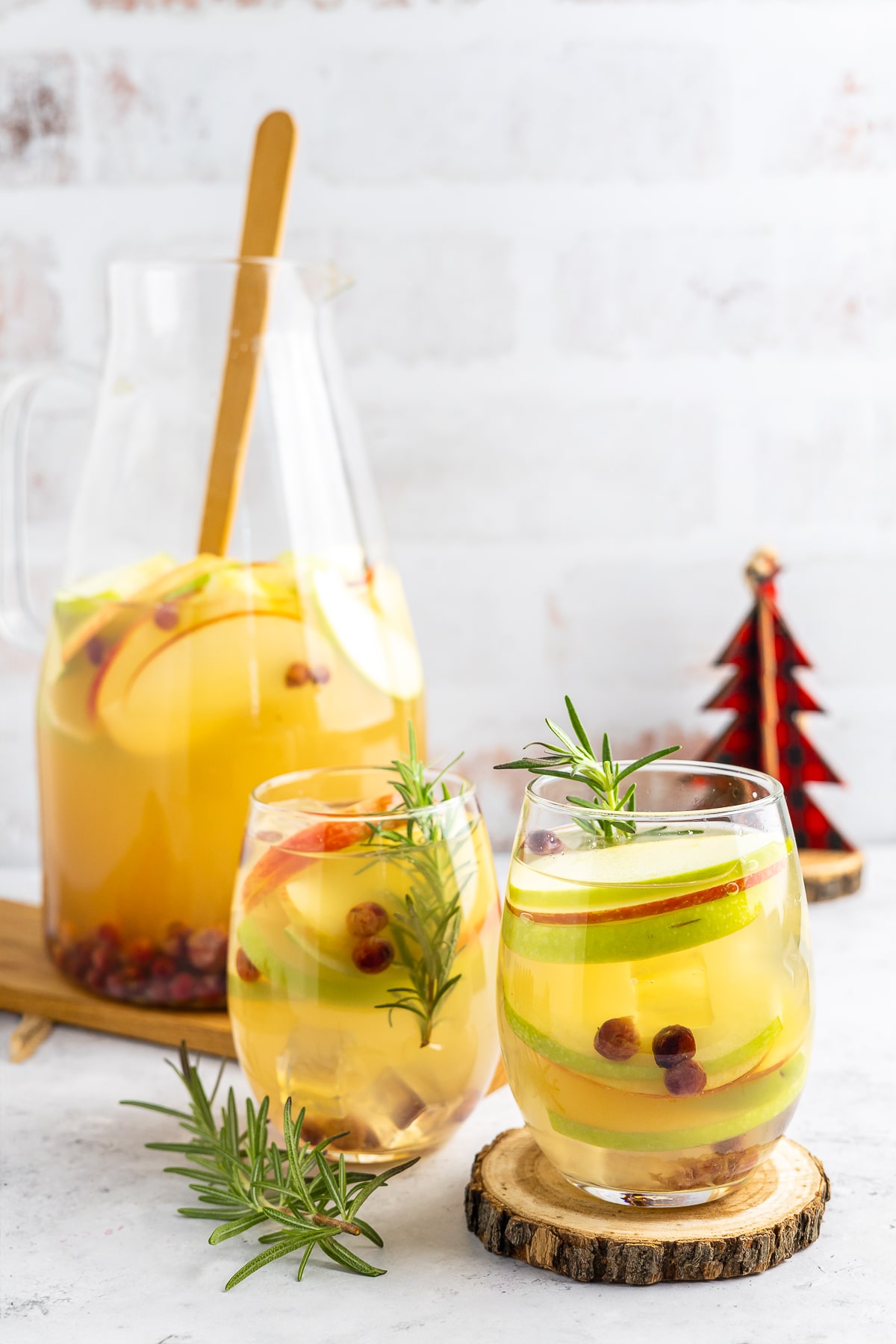 This white wine sangria is light, refreshing and effervescent, with flavors of vanilla, apples, and cranberries. #recipe from thissillygirlskitchen.com #sangria #whitewinesangria #wintersangria #holidaysangria #cranberry #apple #cocktail table set up with pitched or Winter Sangria and glasses of it