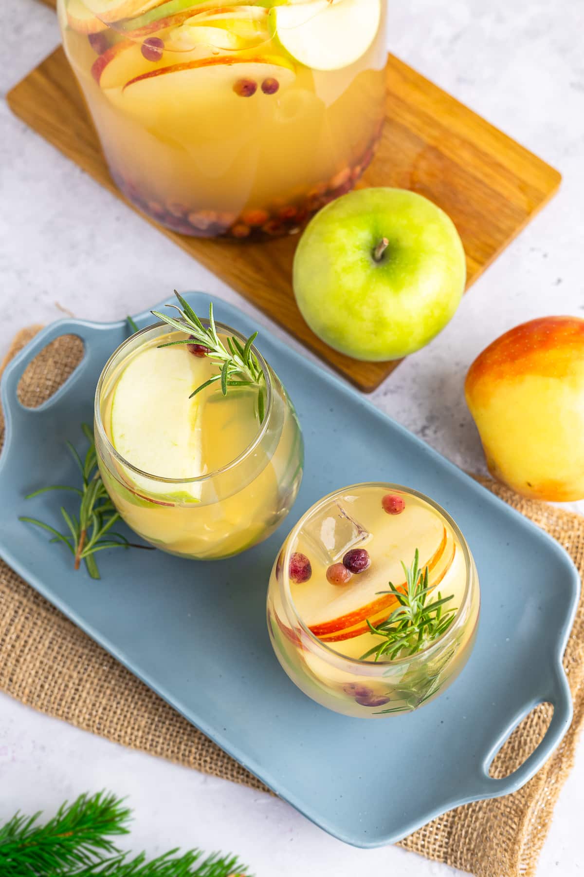 This white wine sangria is light, refreshing and effervescent, with flavors of vanilla, apples, and cranberries. #recipe from thissillygirlskitchen.com #sangria #whitewinesangria #wintersangria #holidaysangria #cranberry #apple #cocktail overhead images of Winter Sangria served on a blue tray