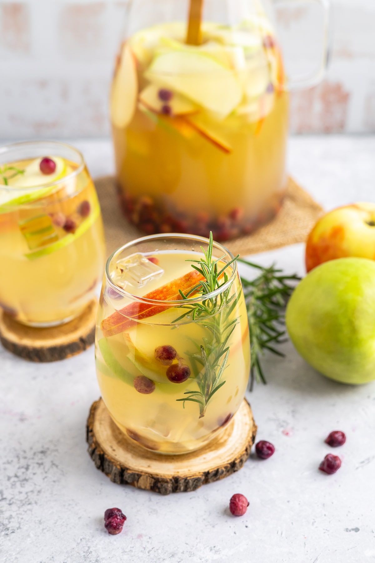 This white wine sangria is light, refreshing and effervescent, with flavors of vanilla, apples, and cranberries. #recipe from thissillygirlskitchen.com #sangria #whitewinesangria #wintersangria #holidaysangria #cranberry #apple #cocktail Winter Sangria served in wine glasses with garnishes
