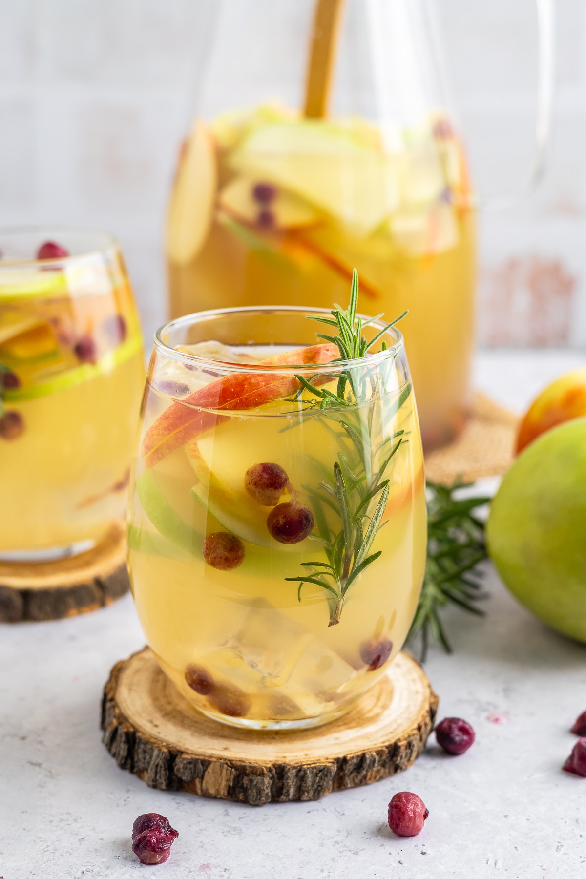 This white wine sangria is light, refreshing and effervescent, with flavors of vanilla, apples, and cranberries. #recipe from thissillygirlskitchen.com #sangria #whitewinesangria #wintersangria #holidaysangria #cranberry #apple #cocktail up close images of Winter Sangria in glasses with garnishes