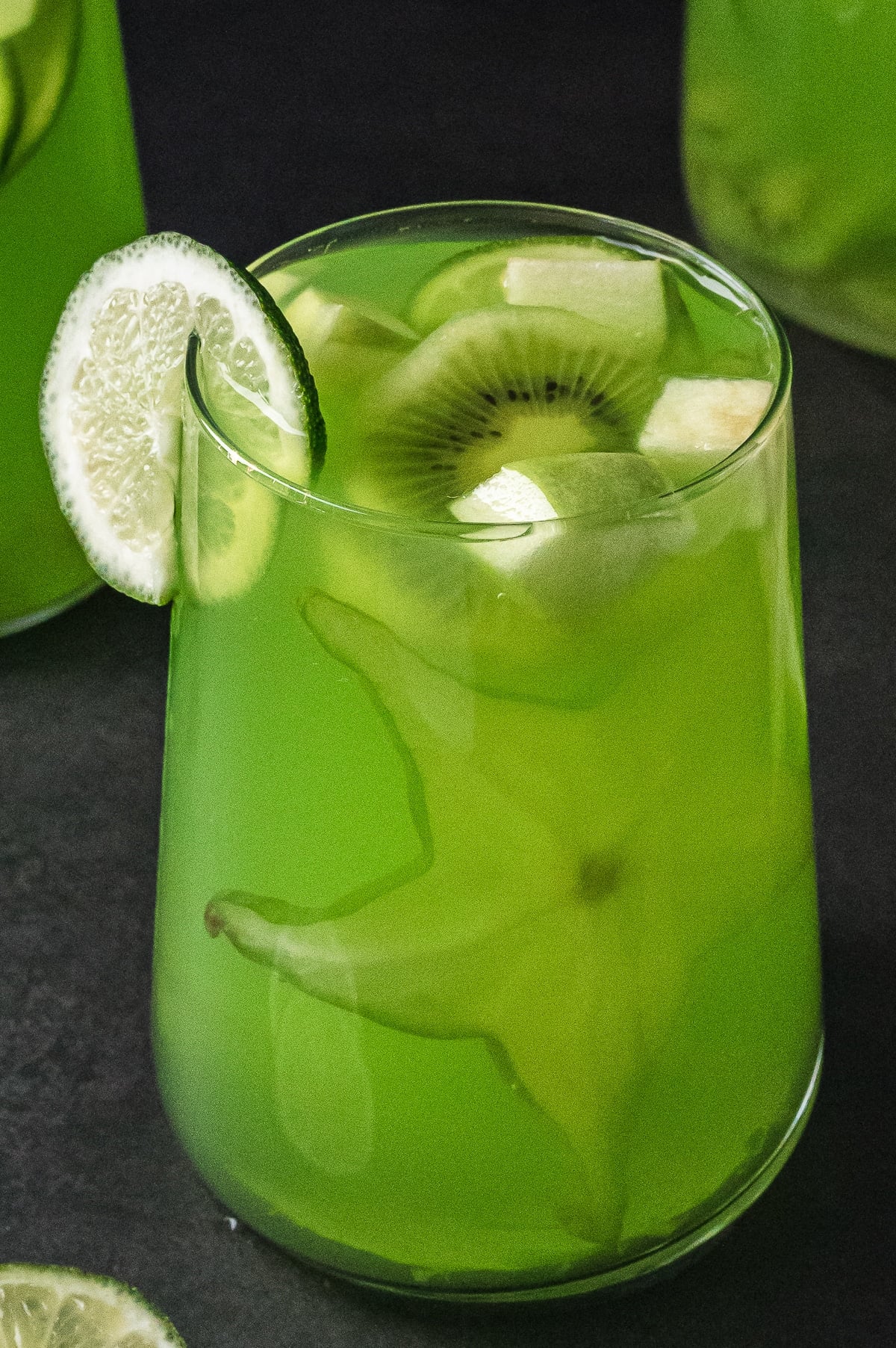 up close image of Green Punch in a wine glass with garnishes