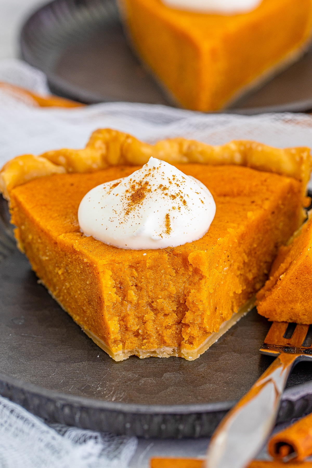 a slice of Sweet Potato Pie on a metal plate with a bite taken out