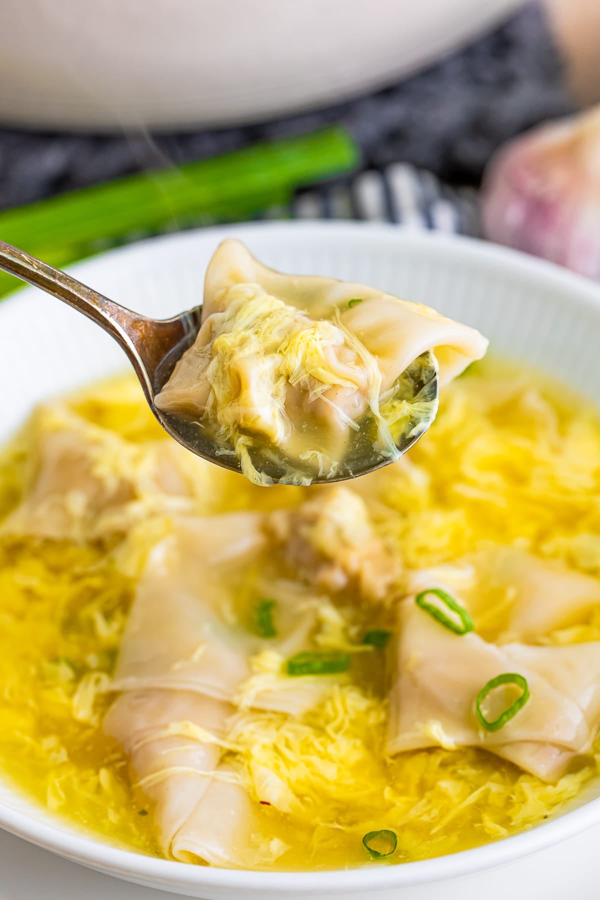 a spoon holding up one wontover over Wonton Egg Drop Soup