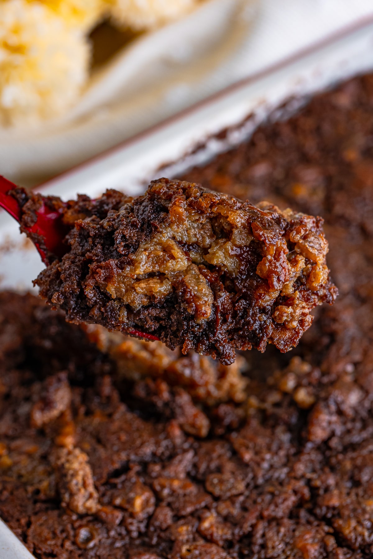 a serving spoon holding up a portion of Pecan Cobbler in air