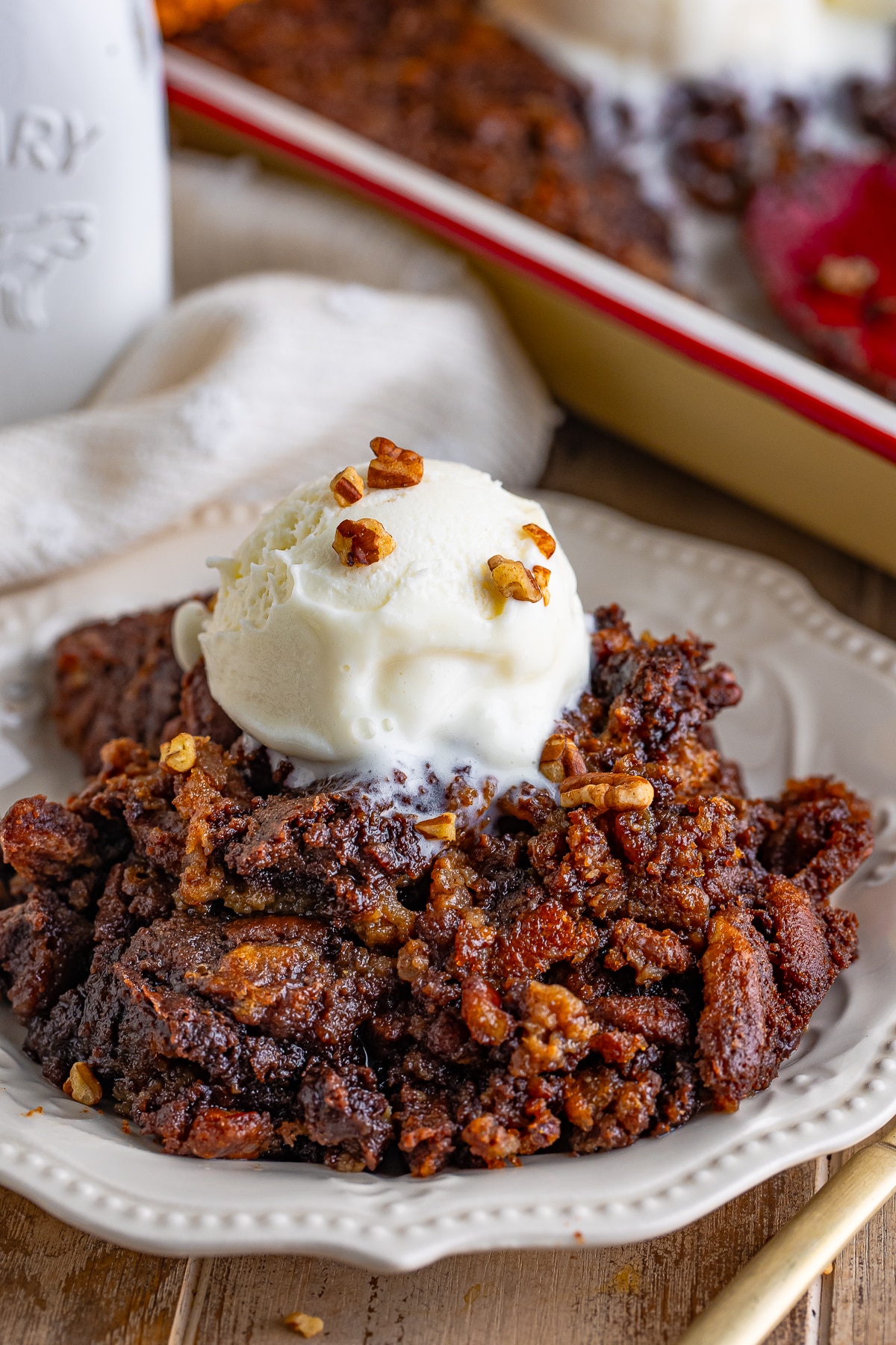 Pecan Cobbler served on ivory plate on wooden table top with ice cream