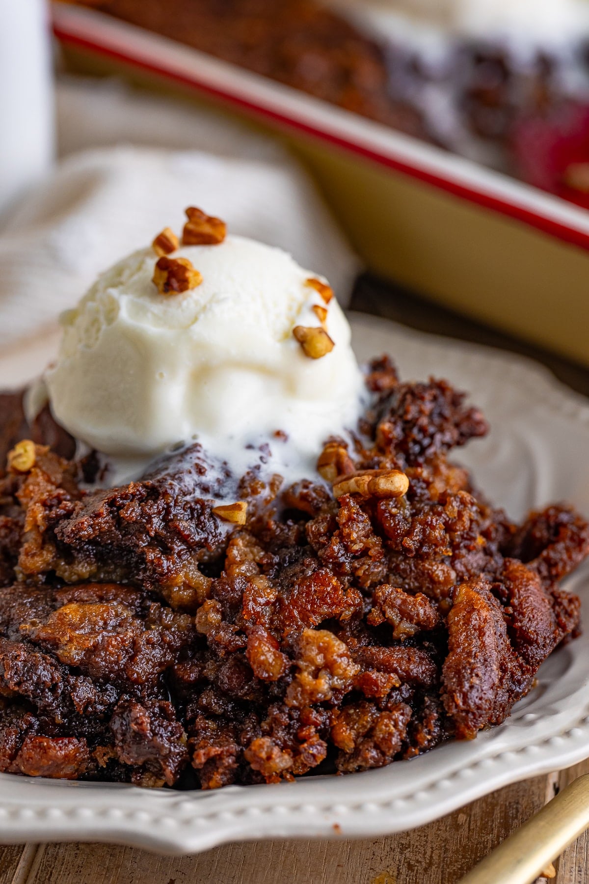 Pecan Cobbler served on an ivory plate with a scoop of ice cream on top