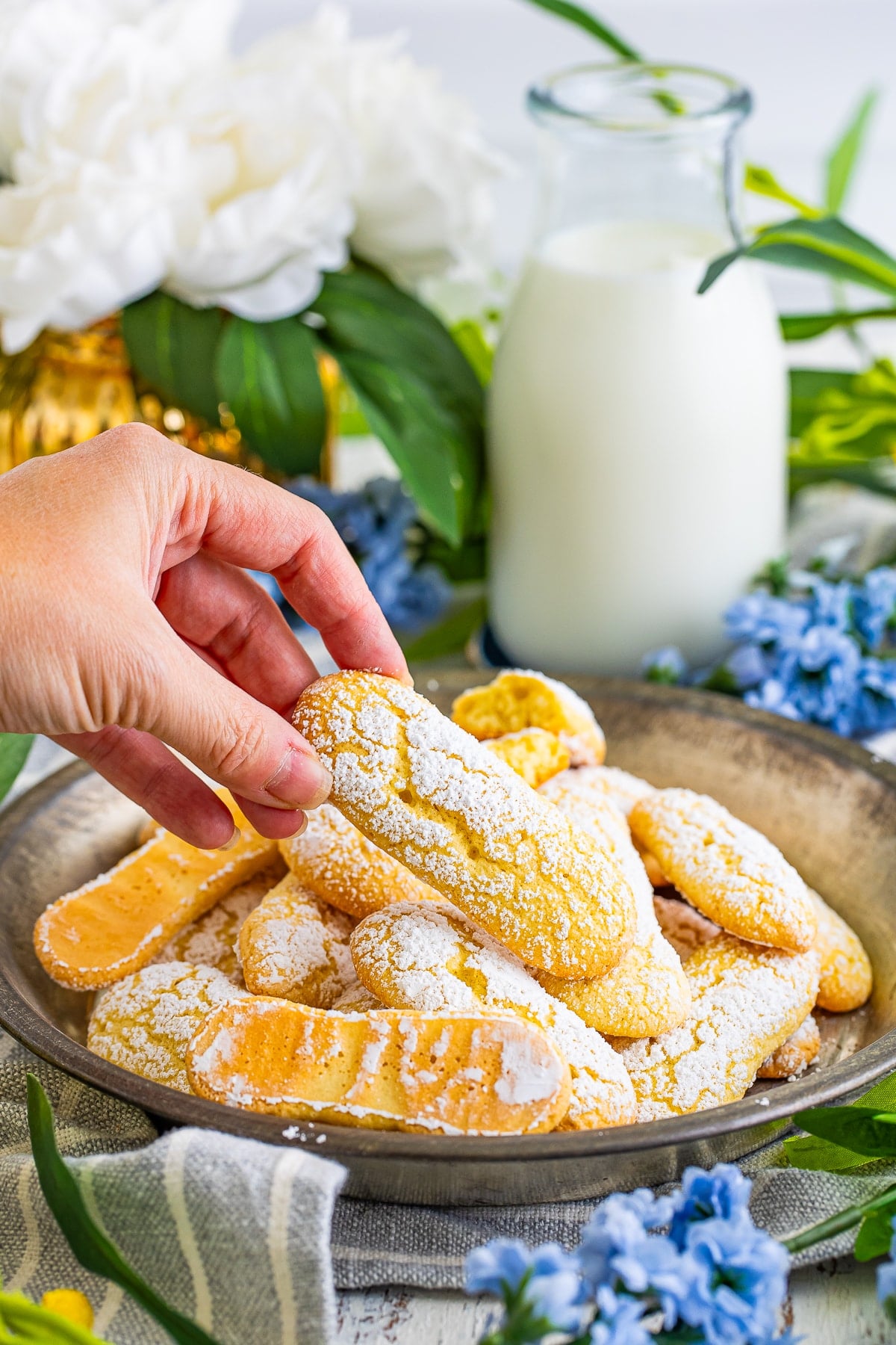 a hand grabbing Lady Finger cookies from serving platter