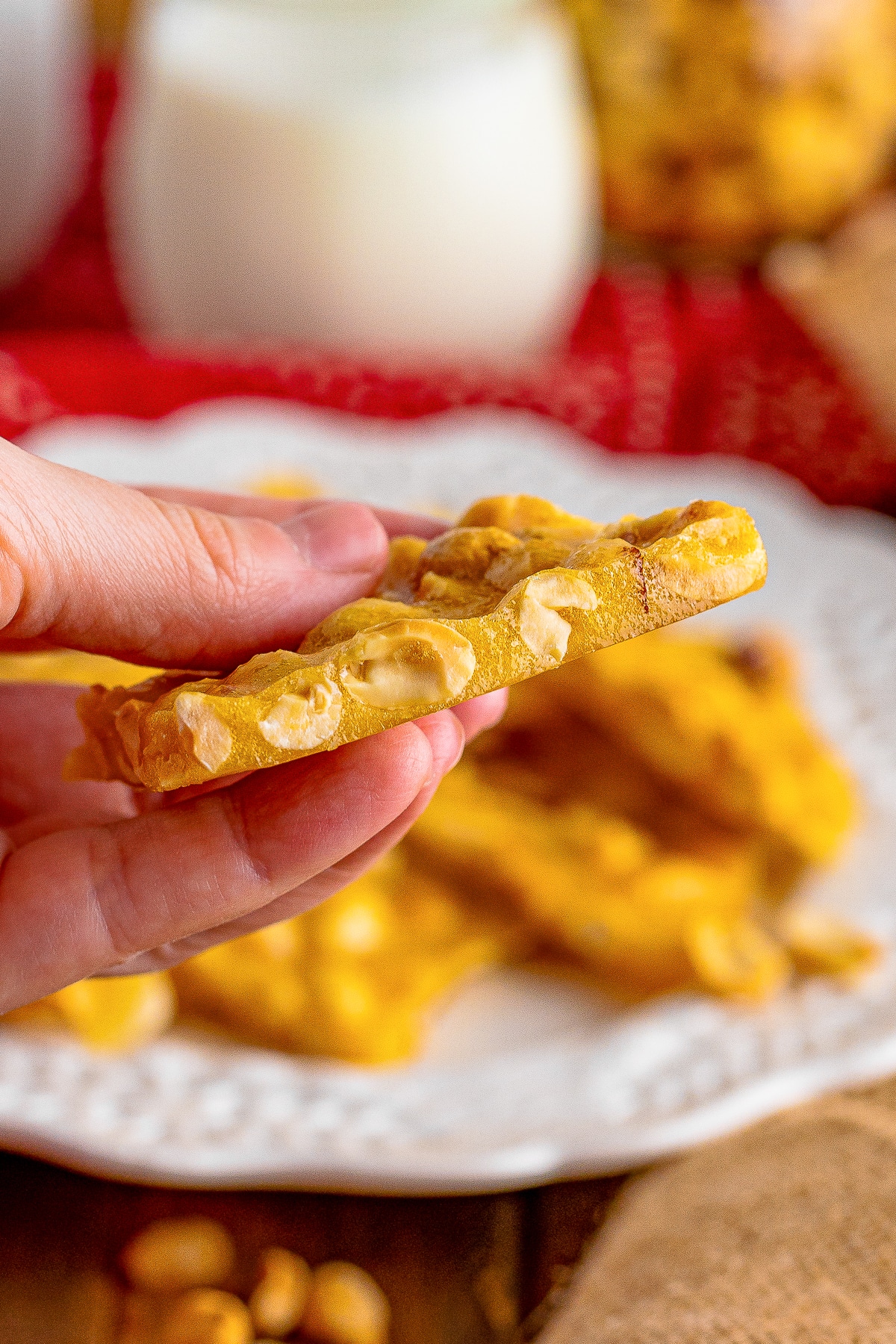 a hand holding up a piece of Microwave Peanut Brittle in air