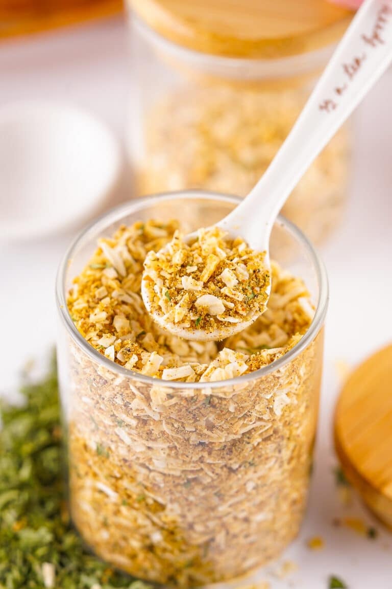 A spoon scooping Homemade Onion Soup Mix from a glass storage jar.