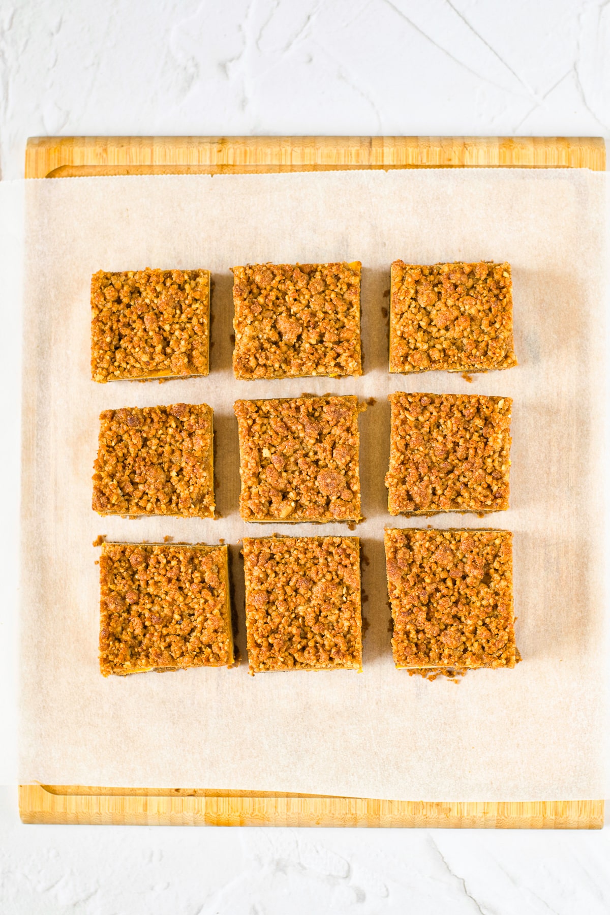 finished Pumpkin Cheesecake Bars cut into squares on parchment paper, overhead image