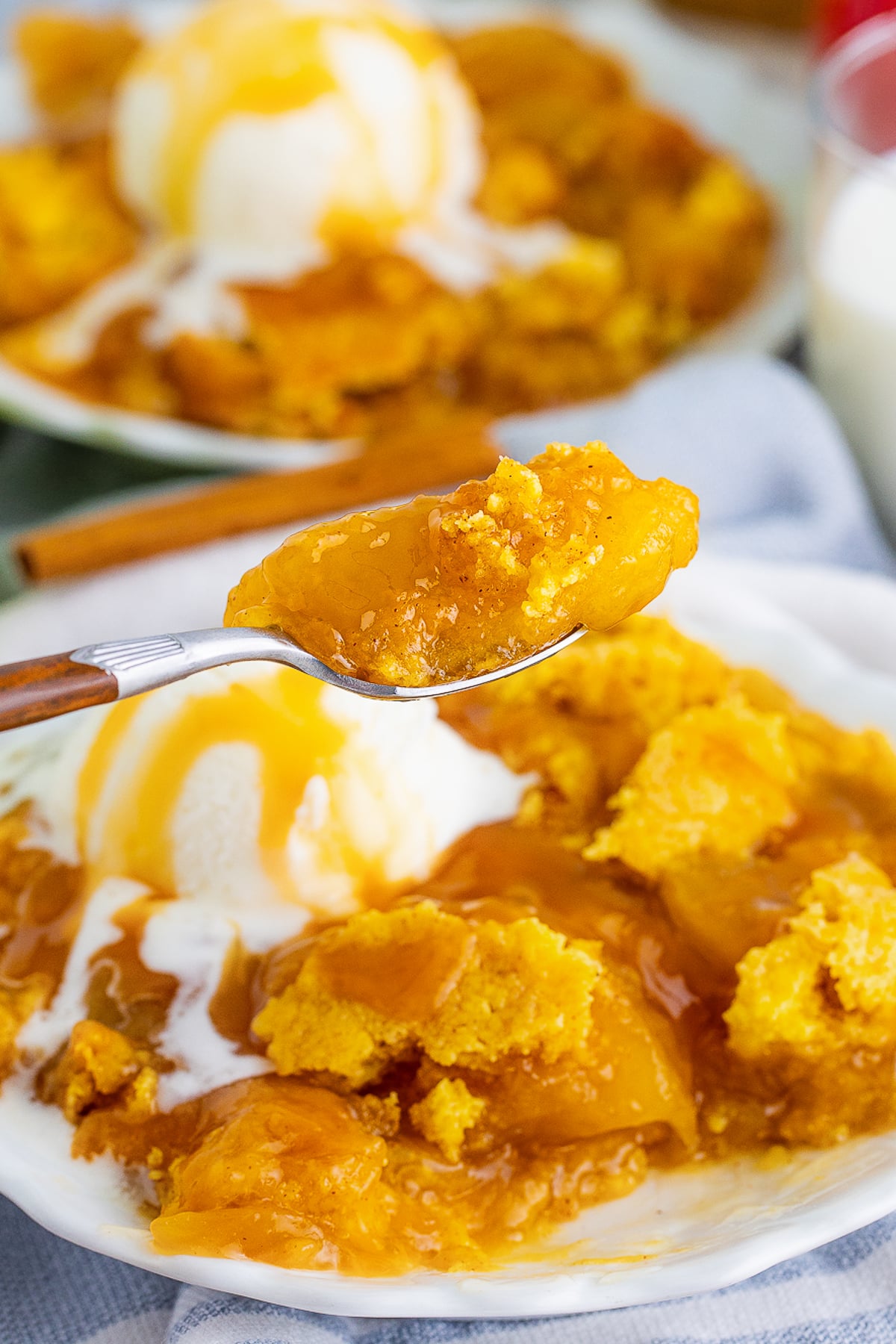 a spoon holding up a bite of Caramel Apple Dump Cake in air