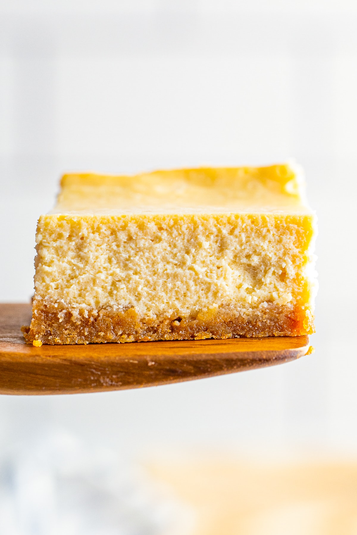 a spatula holding up a piece of Maple Cheesecake in air
