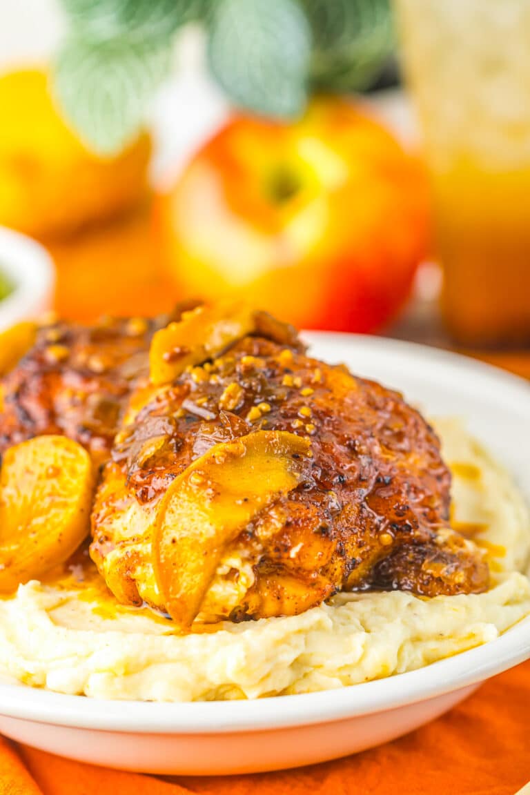Apple Cider Chicken thigh glazed and golden over mashed potatoes with tender apple slices.