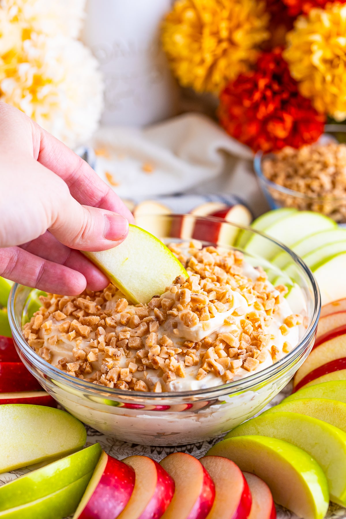 a hand dipping an apple slice into a bowl of Caramel Apple Dip