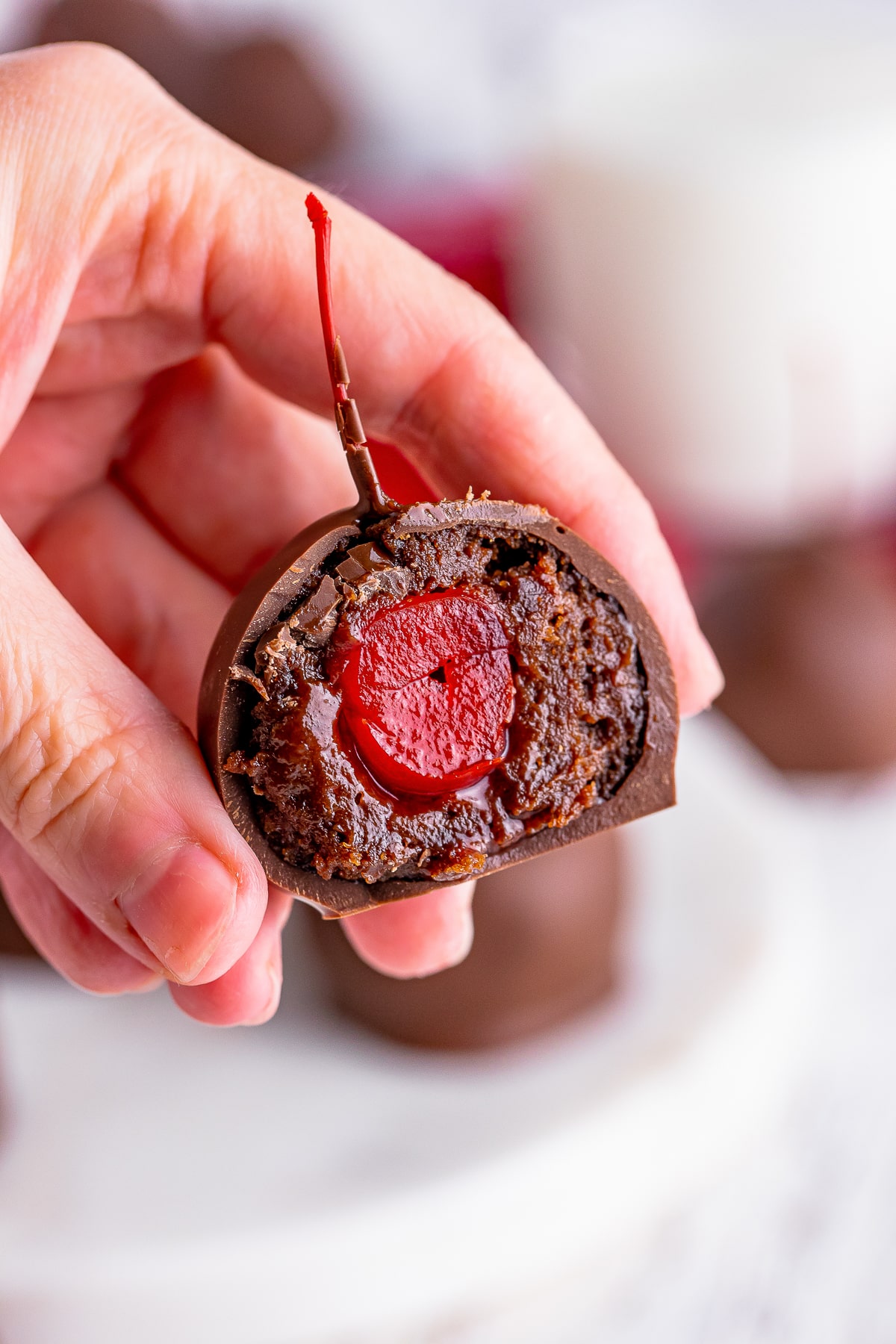 a hand holding up Brownie Truffles in air that has been cut in half