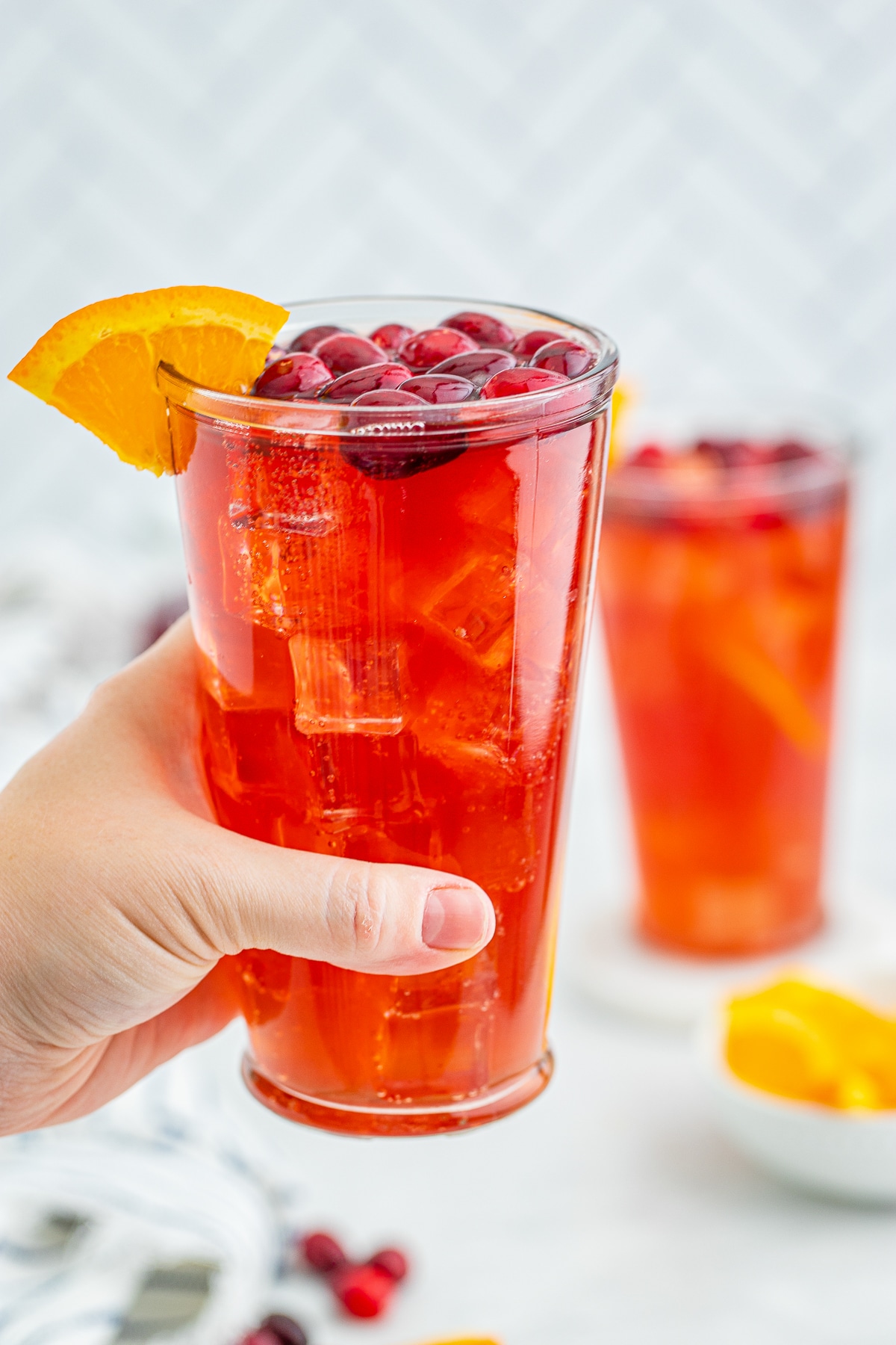 a hand holding up a glass of Rum Punch in air